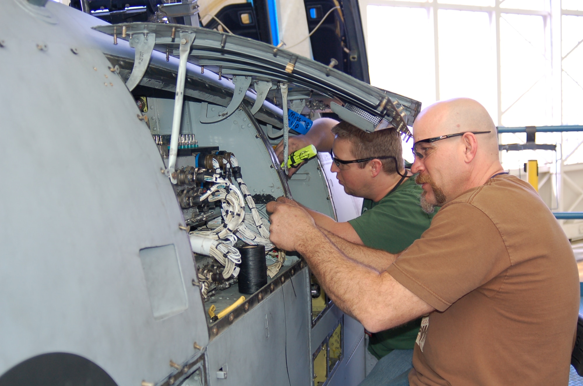 Dennis Miller (right) and Chris Ward inspect the wiring in A-10 panels before sending the aircraft to the fuel dock. (Air Force photo by Bill Orndorff)

