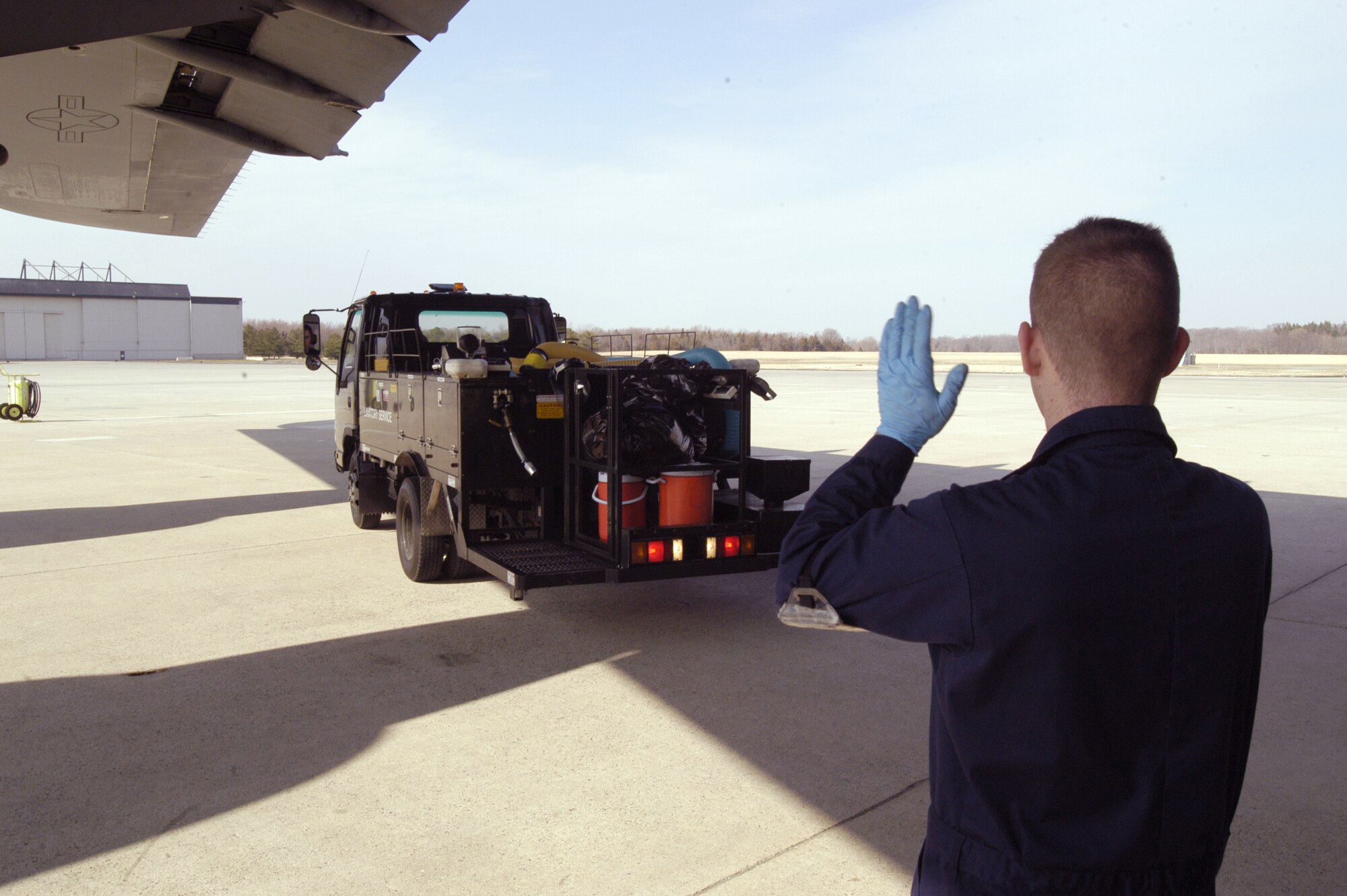 DOVER AIR FORCE BASE, Del. -- Airman 1st Class Douglas Kellogg carefully guides one of 436th Aerial Port Squadron Fleet Services Flight's Latrine Servicing Trucks, driven by Airman 1st Class Alex Hoover, safely toward a C-5 here.  The flight not only cleans and services all aircraft lavatories, but also removes trash on board, prepares all outbound aircraft with pillows, blankets and other necessary items, and delivers all passenger and crew meals. (U.S. Air Force photo/Senior Airman James Bolinger)                           