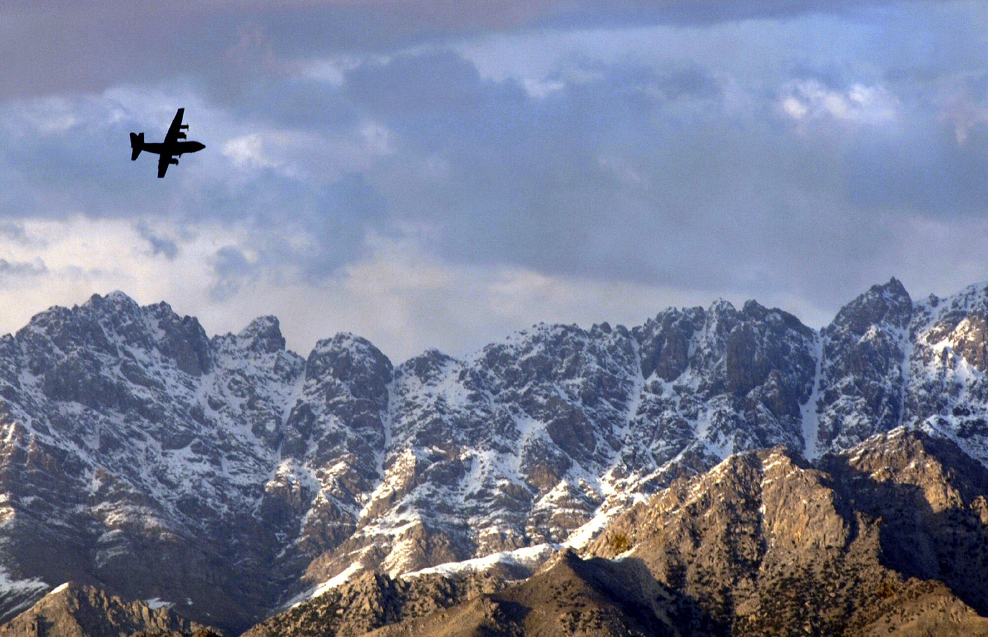 A C-130 Hercules flies over mountainous Afghanistan terrain March 22 on the way to deliver supplies to Bagram Air Base. (U.S. Air Force photo/Tech. Sgt. Cecilio M. Ricardo Jr.)
