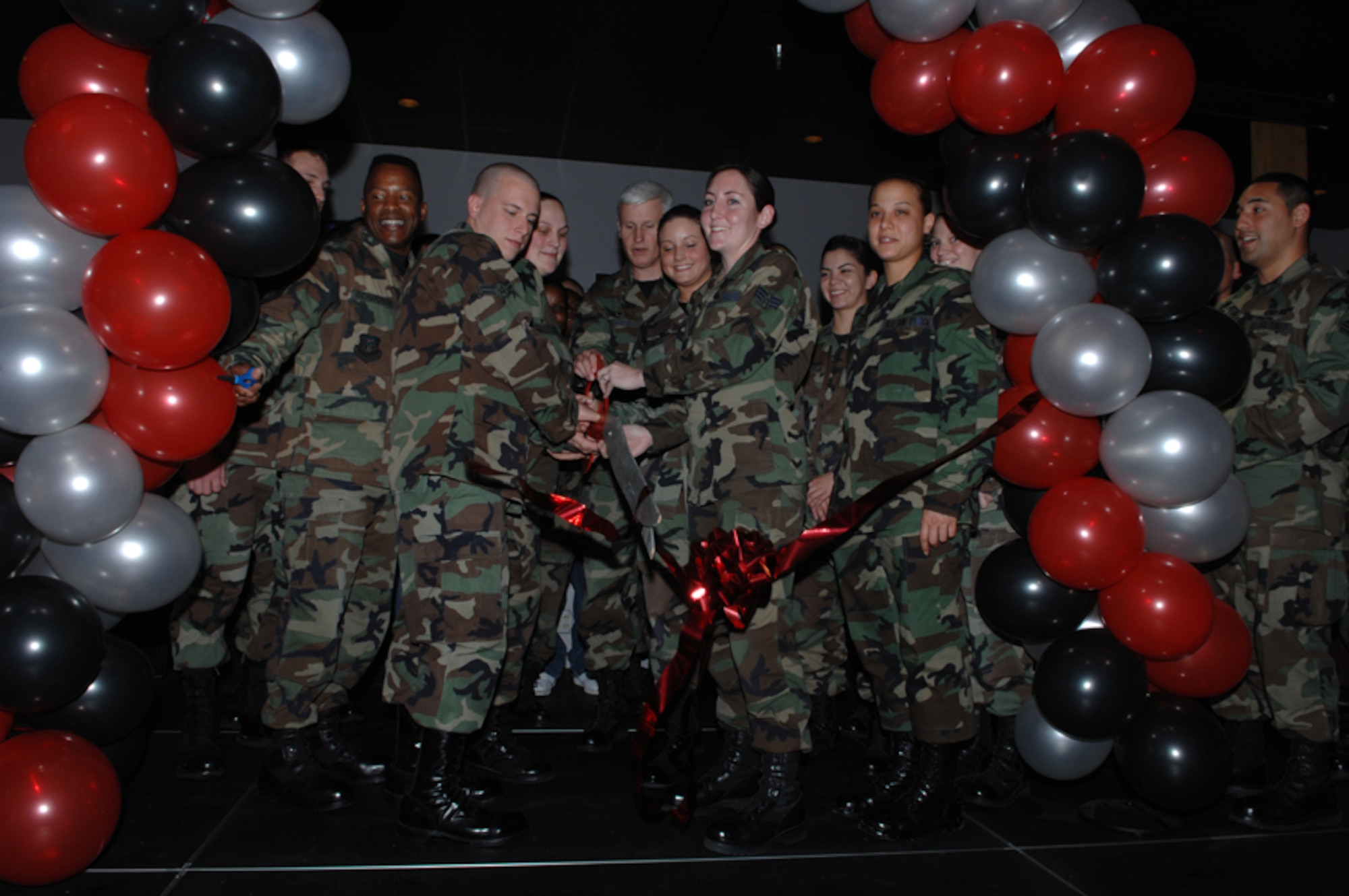 Col. Norman Brozenick Jr. (center), 1st Special Operations Wing commander, and Chief Mast Sgt. Jeffrey Richardson (left), 1st SOW command chief, assist in the ribbon cutting for The Landing Zone March 15. (U.S. Air Force photo by Senior Airman Cynthia Morrow)