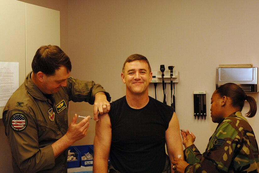 Brig. Gen. Burt Field, 1st Fighter Wing commander, receives a Typhoid shot by Col. Kory Cornum 1st Medical Group commander (left) and an  Anthrax shot by Staff Sgt. Renea McCoy, 1st Aerospace Medicine Squadron aerospace medical technician March 23. Members who receive orders to Korea or U.S. Central Command must begin or continue the series of Anthrax vaccinations. Vaccinations are voluntary for members not in the mandatory groups who have received at least one dose of the vaccine since 1998. For more information, call public health at 764-5252 or visit www.anthrax.mil. (U.S. Air Force photo/Airman Aaron Johnson)  