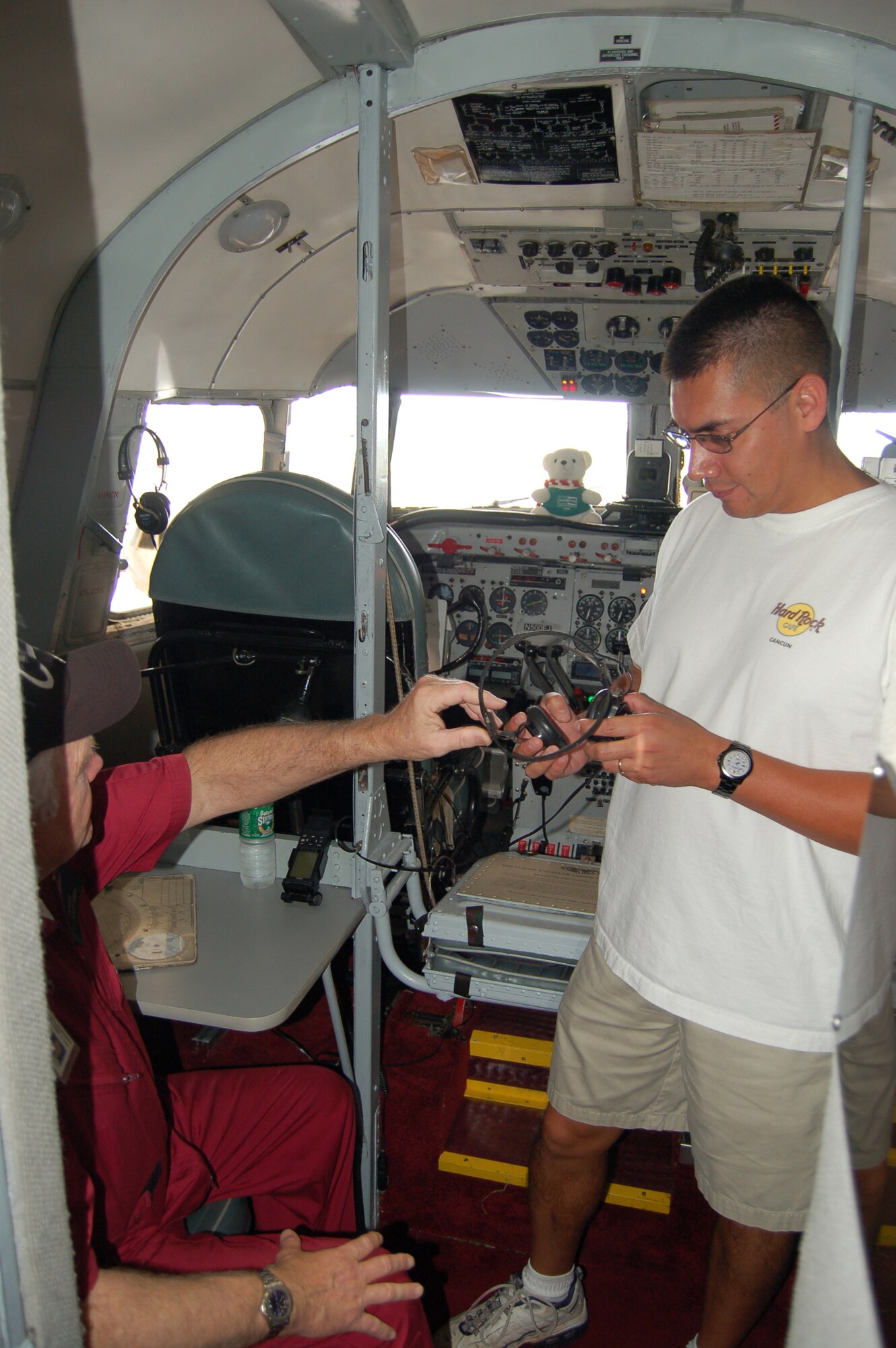 Jim Reed (left) shows Capt. David Saucedo some communications equipment in the cockpit of a C-54 during a March 22 open house at Coast Guard Air Station Borinquen, Puerto Rico. Mr. Reed is a retired technical sergeant and a C-54 flight crew member. Captain Saucedo is the assistant professor of aerospace studies at the University of Puerto Rico. Approximately 500 visitors got a firsthand look at today's military members and equipment in Puerto Rico, and to see the C-54 cargo plane used during the Berlin Airlift. (U.S. Air Force photo/Tech. Sgt. Ben Gonzales)