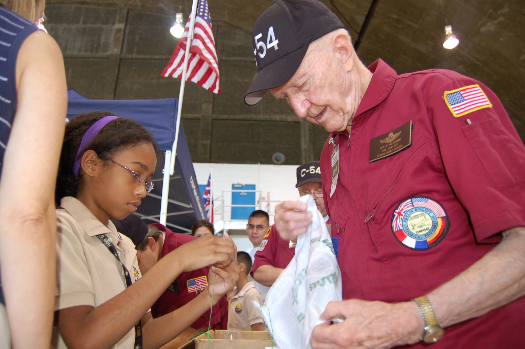 Allyssa Williams learns how to tie a handkerchief parachute to a candy bar from Retired Col. Gail Halvorsen March 22 at Coast Guard Air Station Borinquen, Puerto Rico. Colonel Halvorsen, also known as the Berlin Candy Bomber, flew C-54s during the Berlin Airlift and parachuted candy to children from his airplane. Allyssa, 9, is a Ramey School third grader. Coast Guard Air Station Borinquen is located at what used to be Ramey Air Force Base, which closed in 1973. Approximately 500 visitors got a firsthand look at today's military members and equipment in Puerto Rico, and to see an historic C-54 cargo plane used during the Berlin Airlift. (U.S. Air Force photo/Tech. Sgt. Ben Gonzales)