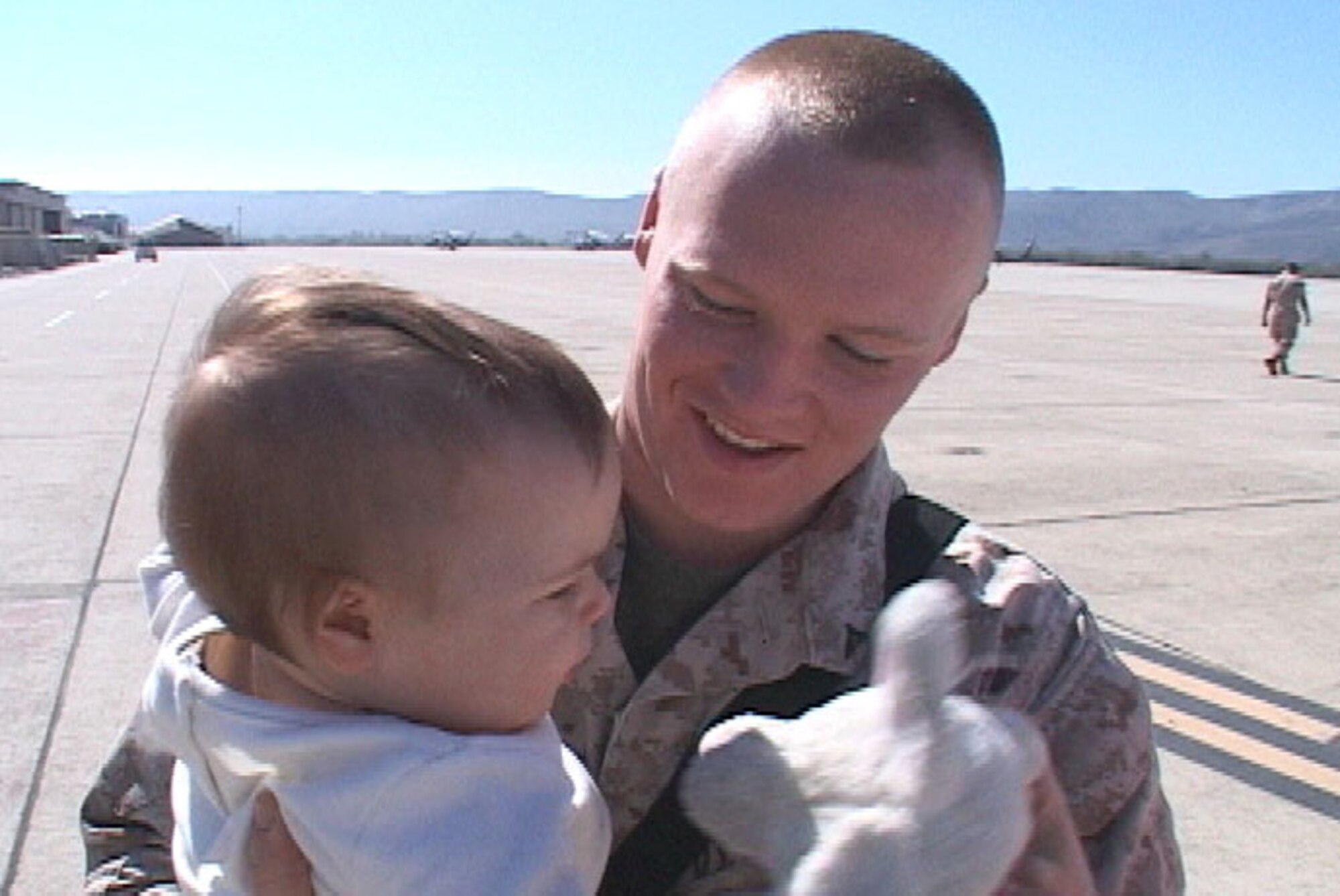 A Marine holds his baby daughter on teh tarmac at Marine Corps Base Camp Pendleton California March 15. The Marine was a member of the rear detachment from Marine Medium Helicopter Squadron 364 returning home following a seven month deployment to Iraq. (U.S. Air Force photo/Army Sgt. Catherine Talento)
