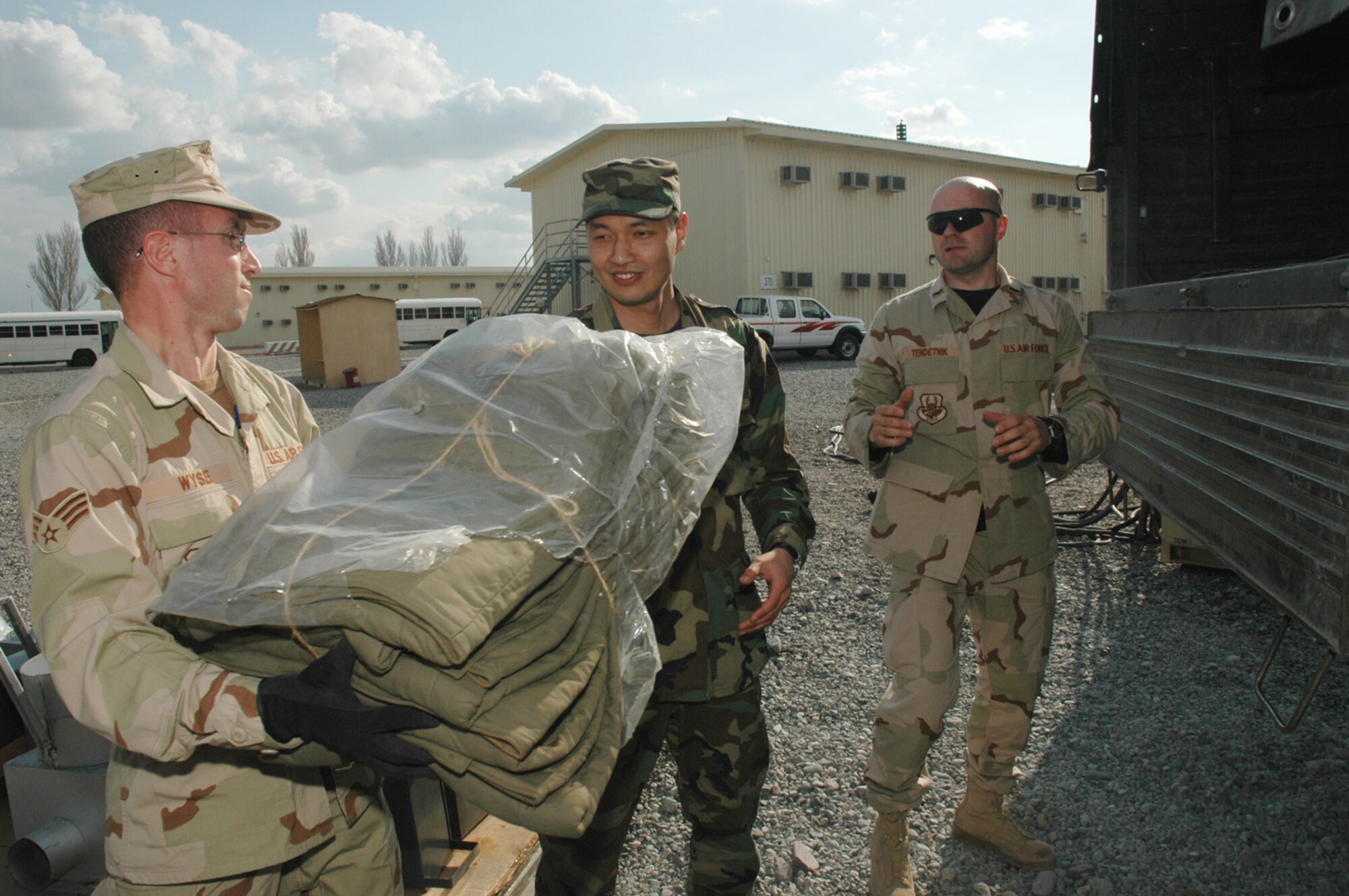 Senior Airman Adam Wyse, 376th Expeditionary Logistics Readiness Squadron,  Senior Lt. Temirbek Torobekov, Chief, Logistics Service, Ministry of Emergency Situations and 1st Lt. Pavel Tendetnik, 376th Air Expeditionary Wing Coalition Coordinator, form a human chain to load a truck with humanitarian goods from the Slovak Republic to Kyrgyzstan. (Air Force Photo/Master Sgt. Daniel Nathaniel)