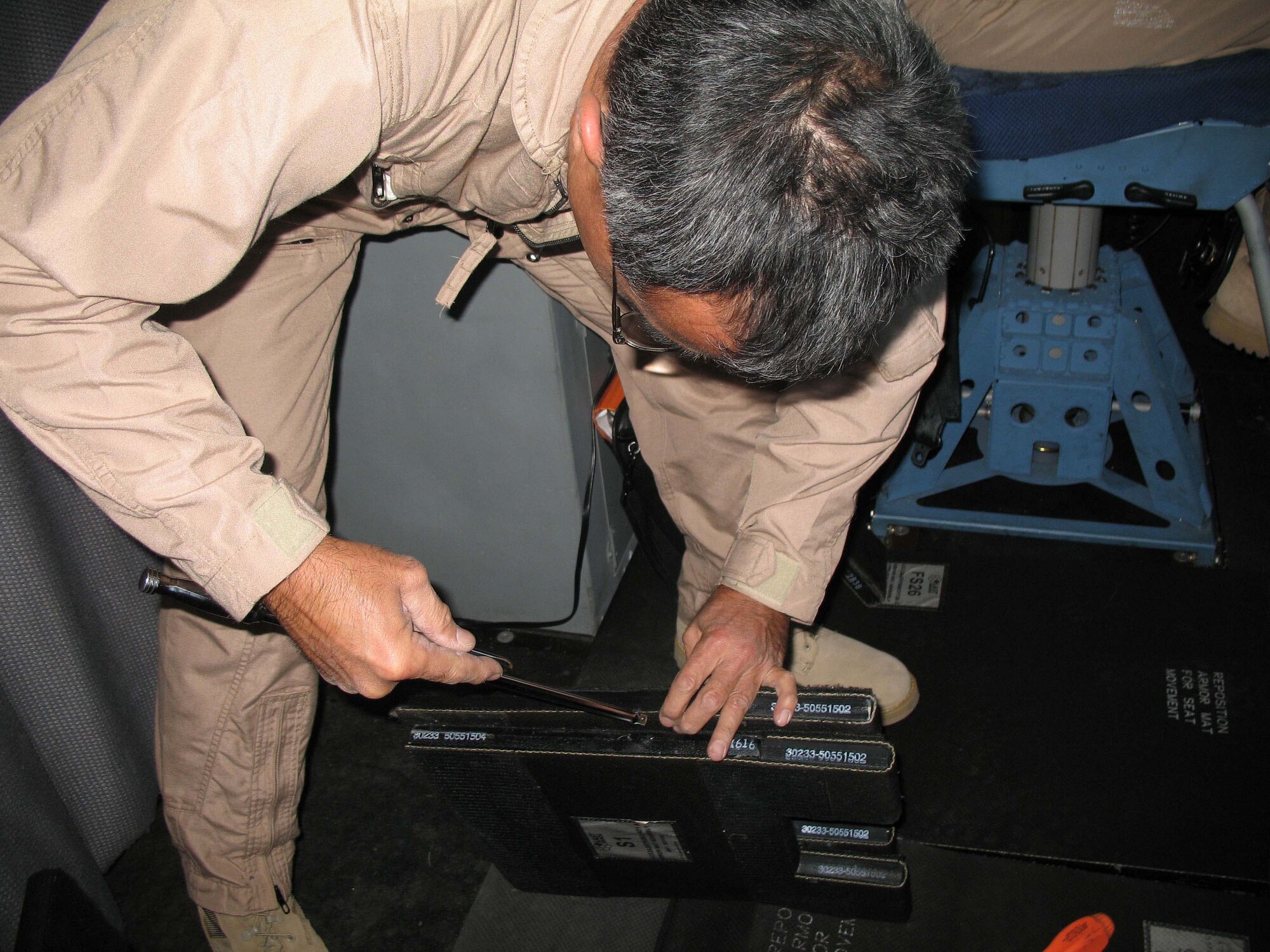 Tech Sergeant Miles Nakamura, a crew chief with the Hawaii Air National Guard's 154th Wing Group, Hickam air Force Base, Hawaii, prepares steel plates for placement in the flightdeck of a C-17 Globemaster III. The plates will provide additional protection to the pilots in the cockpit as they operate in Iraq.(Photo by Army Sergeant Catherine Talento)
