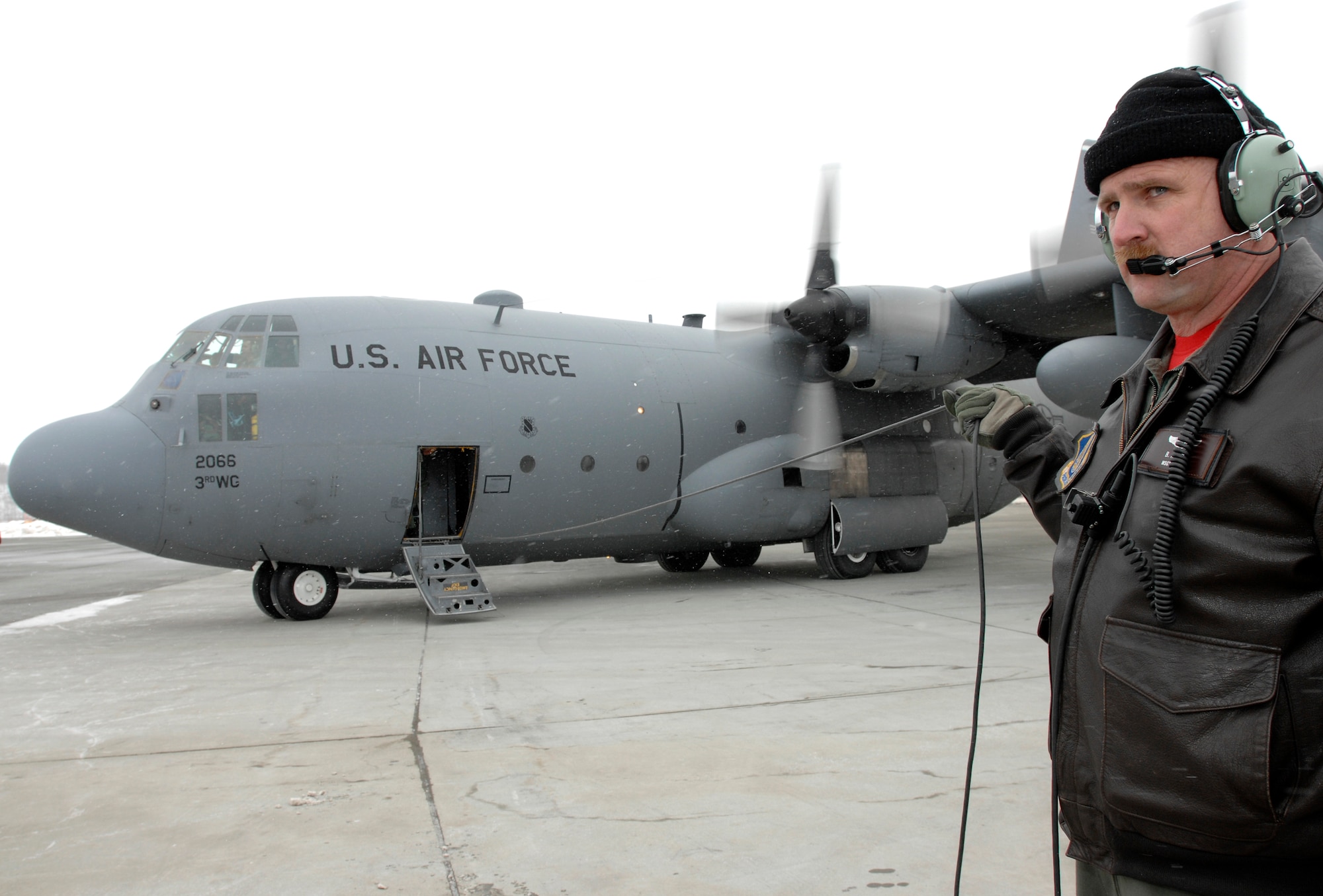ELMENDORF AIR FORCE BASE, Alaska -- Master Sgt B.A. Lund, a loadmaster with the 517th Airlift Squadron, stretches his communication cord to create a "Do not cross line" as he waits for the final passengers to board a C-130. The final C-130 flight March 23 marked the end of the squadron’s C-130 mission here after 43 years of service. The 517th AS is converting C-17s and the C-130s have relocated to Yokota Air Base, Japan, and Dyess Air Force Base, Texas. (U.S. Air Force photo by Tech. Sgt. Keith Brown)