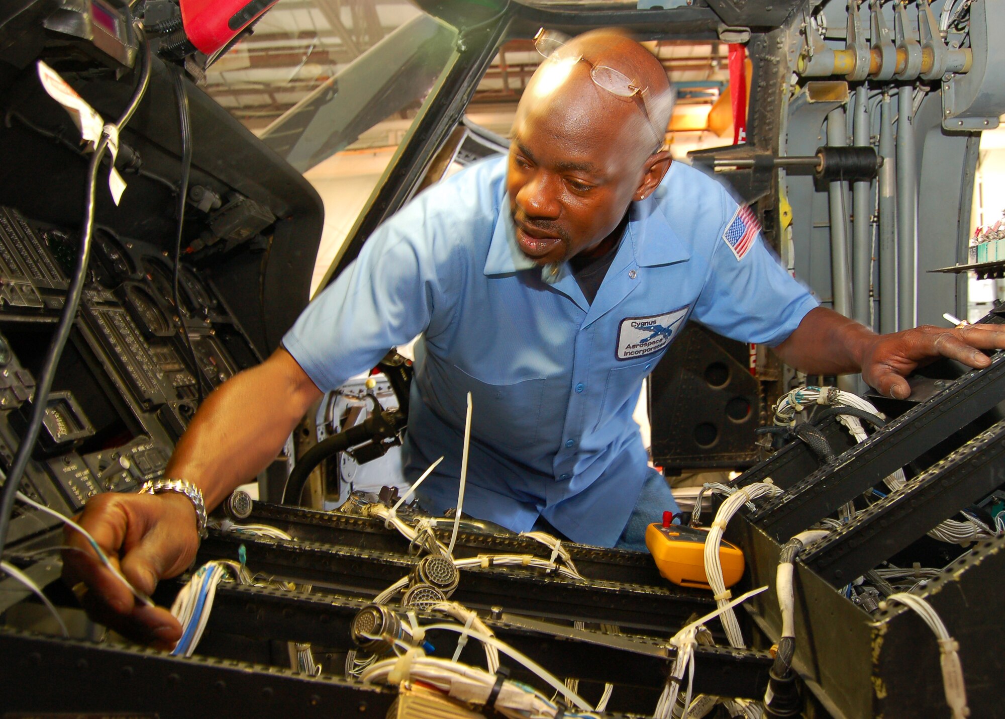 Willie Baker, an avionics technician with Cygnus Aerospace Inc., installs a wiring harness for a Night Vision Imaging System lighting upgrade in a HH-60G Pave Hawk belonging to the 41st Rescue Squadron at Moody Air Force Base, Ga. (U.S. Air Force photo by Tech. Sgt. Parker Gyokeres)