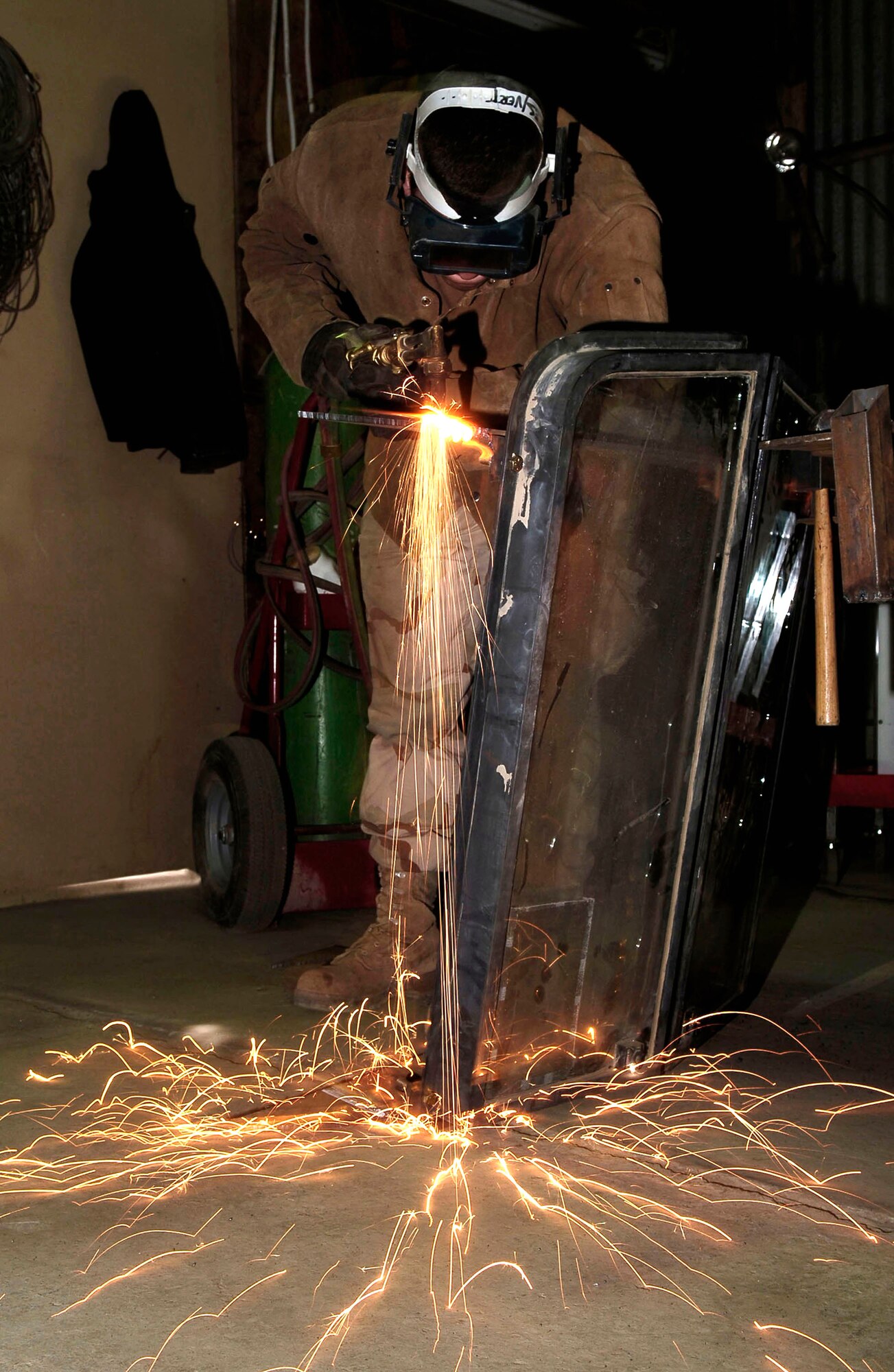 Senior Airman Bradley Burbage cuts off brackets from an old Humvee windshield March 8 at Kirkuk Air Base, Iraq. The windshields are being re-used as added protection for the new security forces towers being built for the base perimeters. Airman Burbage is an arch welder with the 506th Expeditonary Civil Engineer Squadron structures team. (U.S. Air Force photo/Senior Airman Bradley Lail)