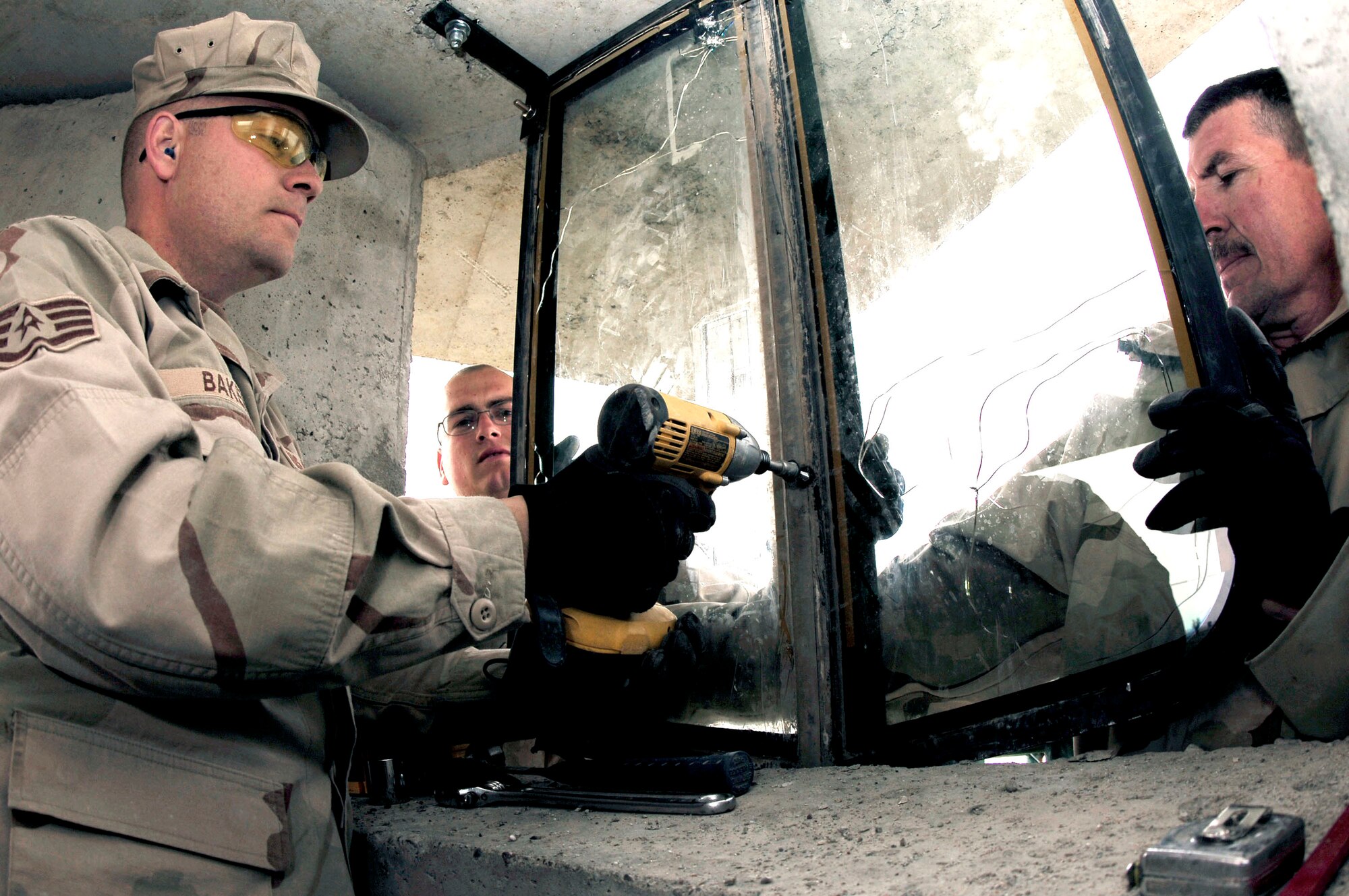 Staff Sgts. Alan Baker and Phillip Lavor and Tech. Sgt. Jonathon LeMaster hang a used Humvee windshield March 15 at Kirkuk Air Base, Iraq. The windshields are being re-used as added protection for the new security forces towers being built for the base perimeters. The Airmen are assigned to the 506th Expeditonary Civil Engineer Squadron structures team. (U.S. Air Force photo/Senior Airman Bradley Lail)