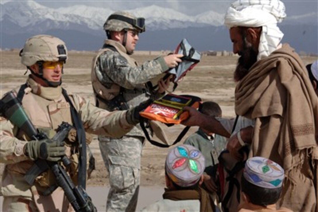 U.S. Air Force Staff Sgt. Bosse (left) and other members of the Gardez Provincial Reconstruction Team give school supplies to children while on a joint patrol with the Afghanistan National Police in the Zormat Province of Afghanistan on March 21, 2007. 