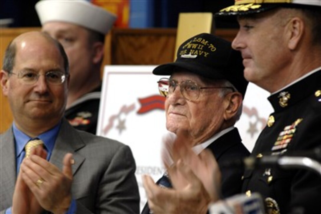 U.S. Navy veteran Paul E. Baker, center, receives applause after receiving a Bronze Star with Combat "V" from the Secretary of the Navy Donald C. Winter, left, in Rochester, N.Y., March 23, 2007. Baker was awarded for his actions 62 years ago on the island of Iwo Jima, while providing care to wounded Marines. 