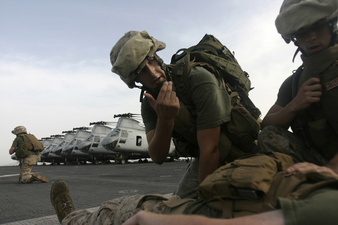 Hospitalman Andrew Garrison, Company E, Battalion Landing Team 2/2, calls a Marine in to help him apply pressure to the wound of the simulated casualty aboard USS Bataan, March 28.  The Marines and Sailors of E Co. were practicing patrolling and evacuation drills to increase the chances of a casualty's survival if one were to occur in combat.