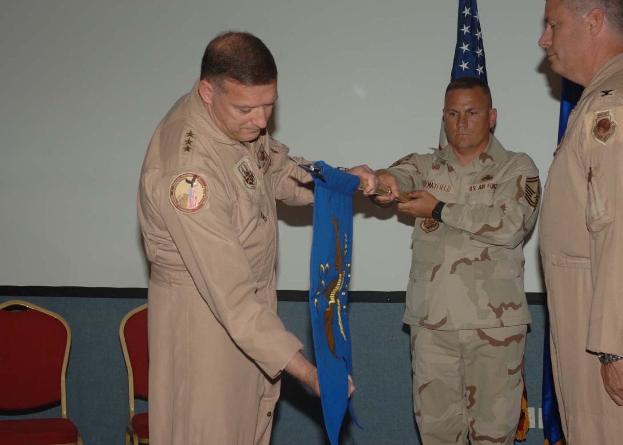 To activate the 363rd Training Group in an official ceremony March 26, U.S. Central Command Air Forces Commander Lt. Gen. Gary North unfurls the unit colors as Col. Michael Cosby, right, stands ready to assume command. The 363rd TG was stood-up on an air base in the Persian Gulf region to facilitate the training of airmen from various nations. (U.S. Air Force photo)