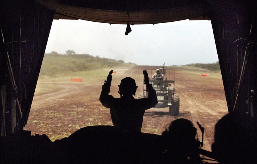 U.S. Air Force Airman 1st Class Bret Oyler, a loadmaster, directs Guam Army National Guardsman Spc. Rick Naputi towards the rear of a C-130 Hercules aircraft on a remote dirt strip in southern Ethiopia Dec. 26, 2006, for the removal of cargo. Oyler is deployed from Elmendorf Air Force Base, Alaska, to the 737th Expeditionary Airlift Squadron at a desert base in Southwest Asia.  (U.S. Air Force photo by Master Sgt. Scott Wagers) (Released)