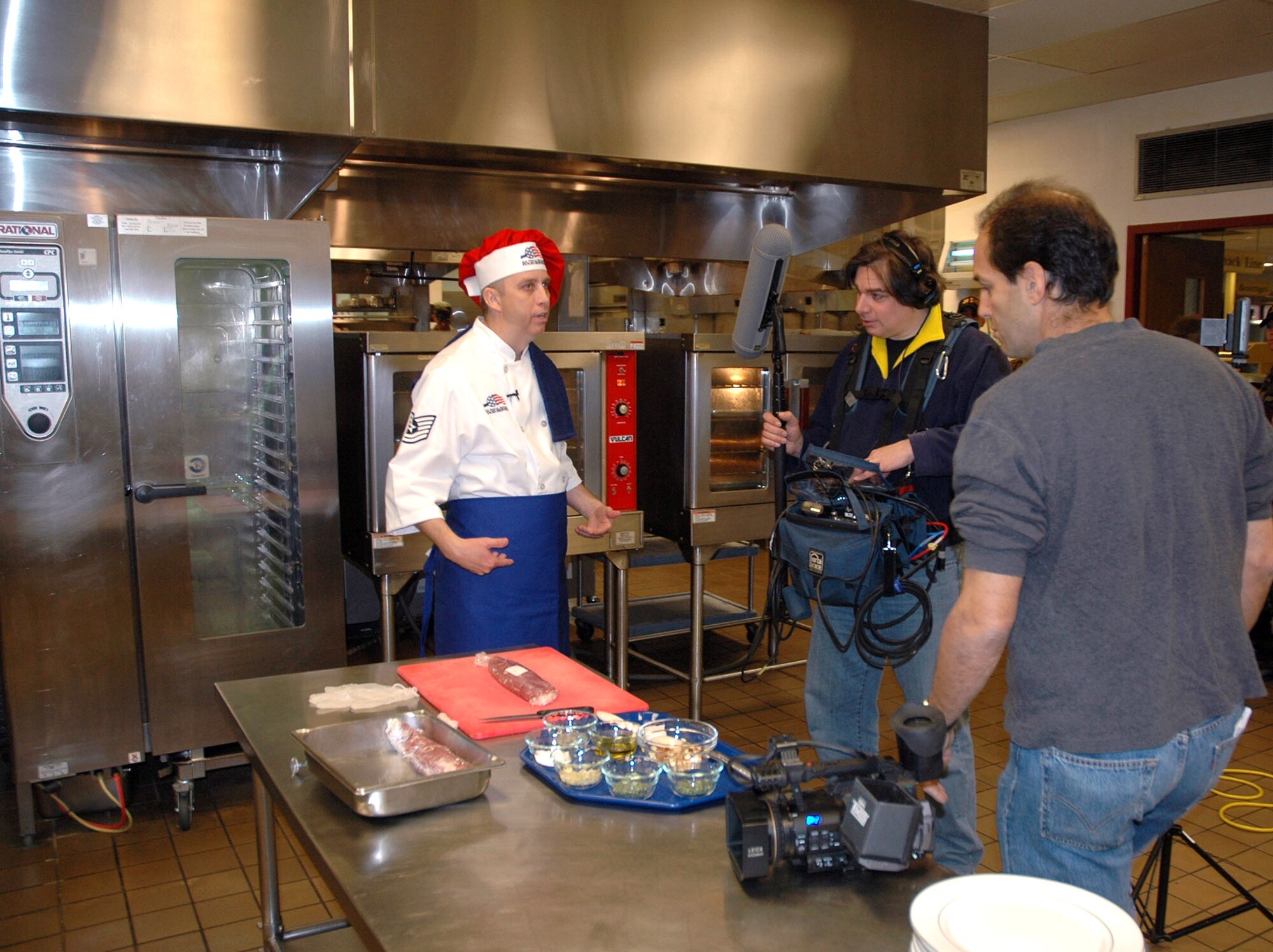 Alan Madison, 'Emeril Live' producer, and Gary Tole, sound technician, prepare to record Tech. Sgt. Wesley Williams cooking his award-winning rainbow fruit-stuffed pork tenderloin at the Ellsworth Air Force Base, S.D. dining facility. The 'Emeril Live' production team recently visited Ellsworth Air Force Base, S.D., to film Sergeant Williams in his kitchen. Sergeant Williams will visit the 'Emeril Live' show April 6 and the episode is scheduled to air sometime in June. (U.S. Air Force photo/Tech. Sgt. Steven Wilson) 