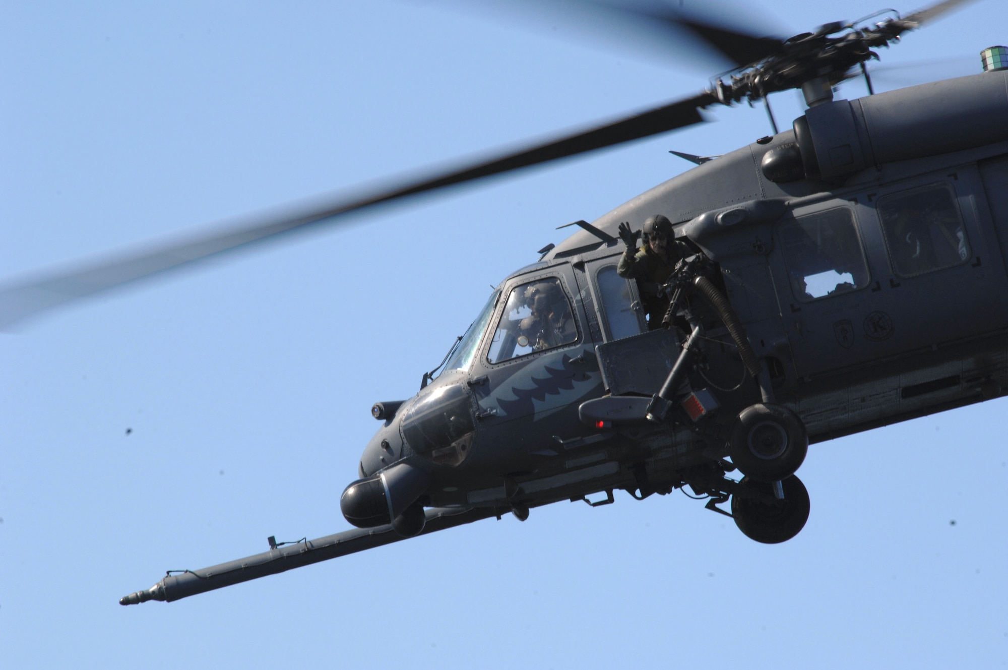 An aerial gunner waves goodbye from the HH-60G Pave Hawk as it flies away with a full load of recovered pararescuemen during a dive recovery exercise March 22 in the Gulf of Mexico. The gunner is assigned to the 41st Rescue Squadron at Moody Air Force Base, Ga. (U.S. Air Force photo/Senior Airman Joshua T. Jasper) 