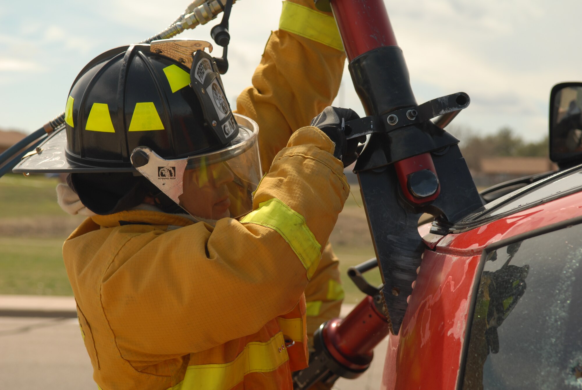 A firefighter attempts to rip open the ceiling of a vehicle used during a natural disaster exercise on Goodfellow Air Force Base March 13. (U.S. Air Force photo by Tech. Sgt. Randy Mallard)