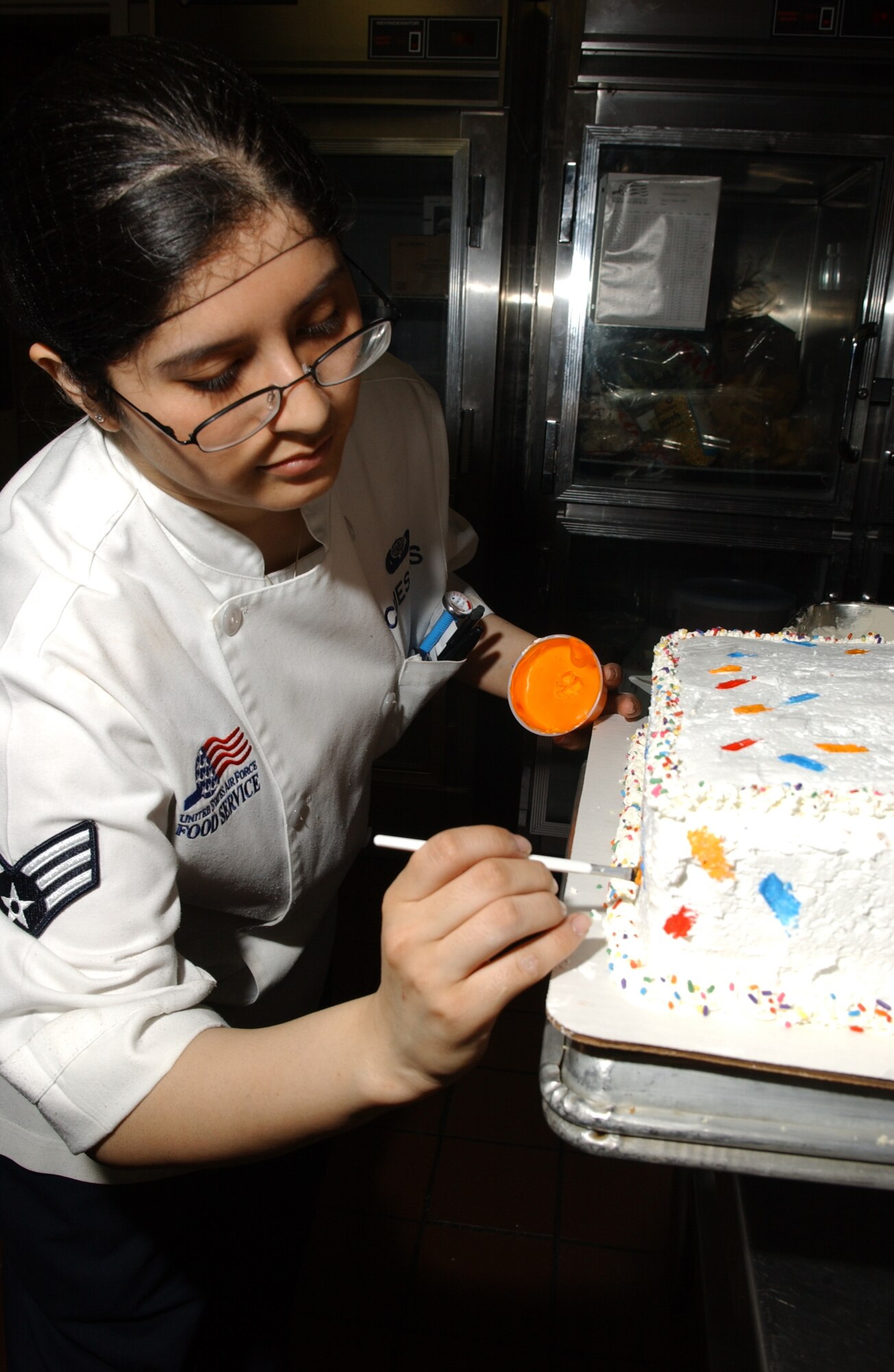 EIELSON AIR FORCE BASE, Alaska -- Senior Airman Cecilia Cuestas, 354th Services Squadron, decorates a two-layered cake for the birthday meal March 22 at the Two Seasons Dinning Facility. The dining facility hosts a birthday meal once every two months for single Airmen unable to spend it with their families. (U.S. Air Force Photo by Airman 1st Class Jonathan Snyder) 