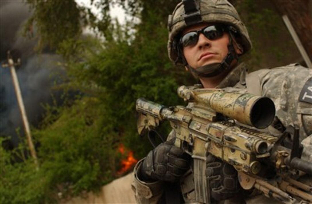 U.S. Army Staff Sgt. Justin Mongold walks down a smoke-filled street in Ghazaliya, Iraq, during a combined cordon and search with the Iraqi army on March 24, 2007.  The smoke is from a controlled detonation set by an explosive ordnance disposal team to destroy a vehicle borne improvised explosive device.  Mongold is attached to Alpha Company, 1st Battalion, 23rd Infantry Regiment, 3rd Stryker Brigade Combat Team, 2nd Infantry Division.  