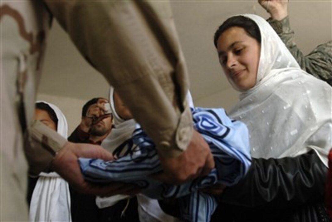 A local Afghan student receives donated school supplies from a Bagram Provincial Reconstructive Team member at Mahmud Raqi High School in Deh Baba Ali, Afghanistan, on March 26, 2007.  The Bagram Reconstructive Team members assisted in building the high school and also donated several bundles of school supplies.  
