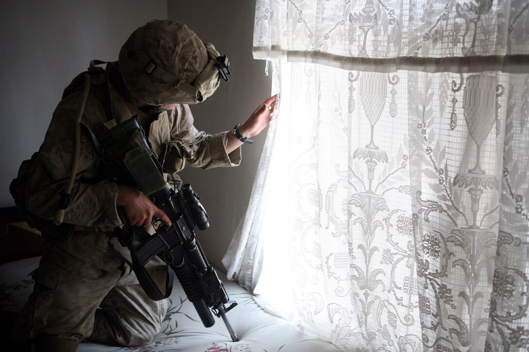 AR RAMADI, Iraq - An infantryman with 2nd Battalion, 5th Marine Regiment, 2nd Marine Division peers out a window hereMany observation posts in Ramadi are former homes of Iraqis now occupied by Marines. Prior to the emplacement of barriers by Marines with Detachment 2, Combat Logistics Battalion 6, these houses provide minimal protection for the infantrymen who inhabit them.