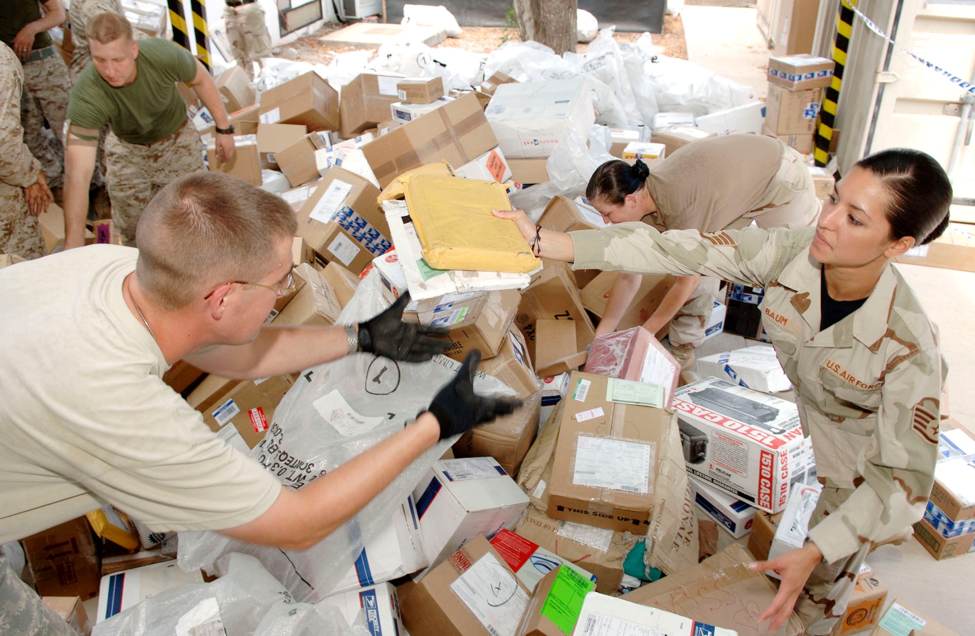 Staff Sgt. Beatriz Baum hands packages to Army Spc. Jay Hohman for sorting at the postal center at Camp Lemonier, Djibouti.  The postal center is the central processing point for all mail and packages slated for service members supporting Joint Task Force Horn of Africa. (U.S. Air Force photo/Daren Reehl)
