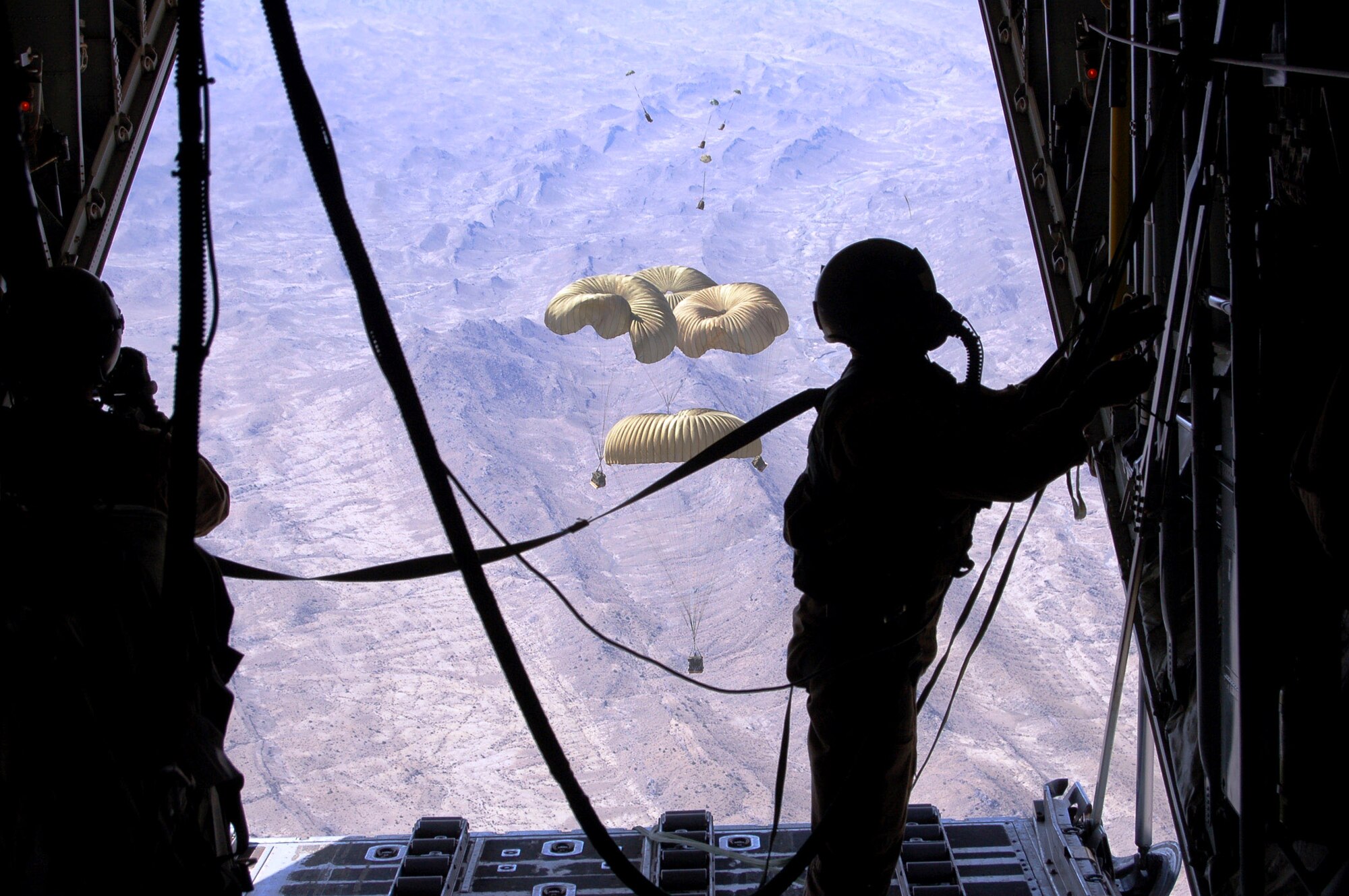 A C-130 Hercules loadmaster observes Improved Container Delivery System bundles March 27 that were airdropped over Afghanistan to replenish supplies for U.S. ground forces supporting Operation Enduring Freedom. (U.S. Air Force photo/Senior Master Sgt. Andy Huneycutt)