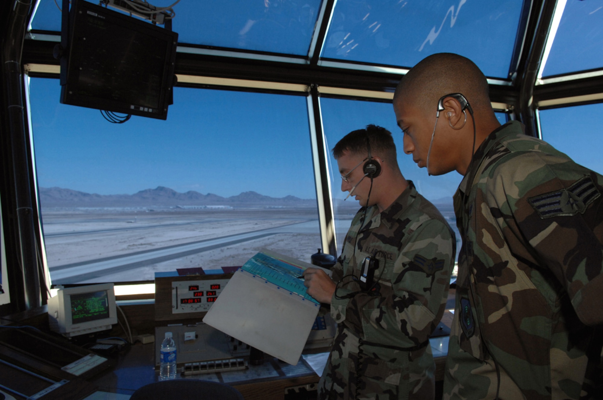 Senior Airman Lynn Jackson receives a briefing from Airman 1st Class Scott Apple in the Nellis Control Tower March 27, 2007. Airman Jackson is 'local control' position, which is responsible for runway and air space operations at Nellis Air Force Base, Nev. (U.S. Air Force photo/Airman 1st Class Kasabyan McGarvey)