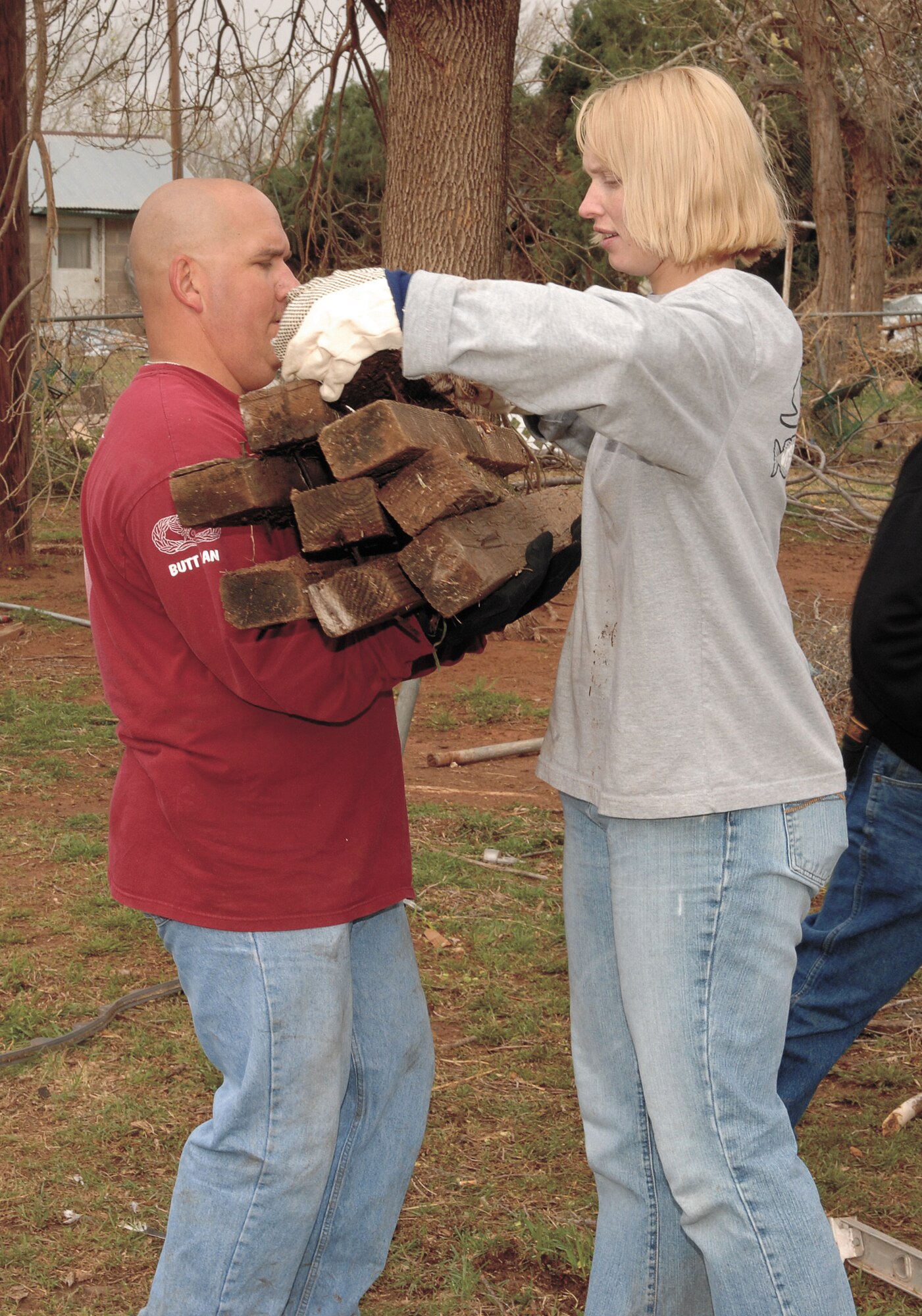 CANNON AIR FORCE BASE, N.M. -- Staff Sgt. Gerri Finan loads up the arms of Master Sgt. Eric Butt with scrap wood from piles of debris. These 27th Communications Squadron Airmen were part of a group of Cannon AFB who assisted in the clean up of Yucca Junior High March 26 in Clovis, N.M. More than 500 volunteers began restoring Clovis, located six miles east of Cannon AFB, after tornadoes swept through the town March 23. (U.S. Air Force photo/Airman 1st Class Randi Flaugh)