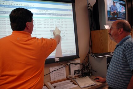 Marc Hoyle (left) and Bill Caldwell (right), both air operation specialists with the 437th Operations Support Squadron, review missions that require diplomatic clearances on a projector screen. (U.S. Air Force photos/Senior Airman Sam Hymas)