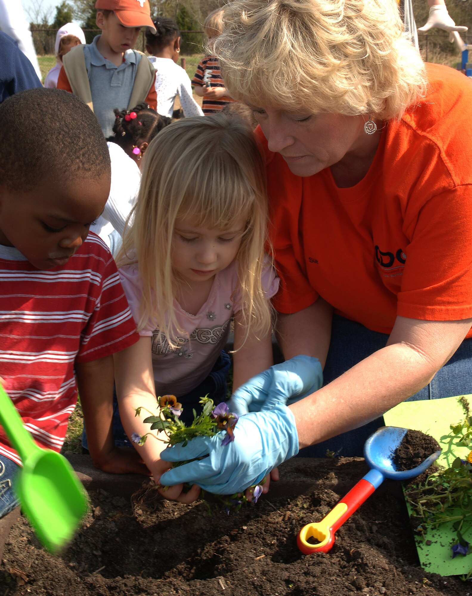 Deonte Shine, son of Staff Sgt. Deonte and Senior Airman Destiny Shine, 1st Equipment Maintenance Squadron, and Anna Robinson, daughter of Amy Robinson, 1st Fighter Wing Public Affairs, help Sue Bonner, Russ Child Development Center childcare provider, plant flowers for spring at the CDC March 28. Children also planted vegetable gardens made of corn, carrots, strawberries and canteloupe. (U.S. Air Force photo/Senior Airman Michelle Arslan) 