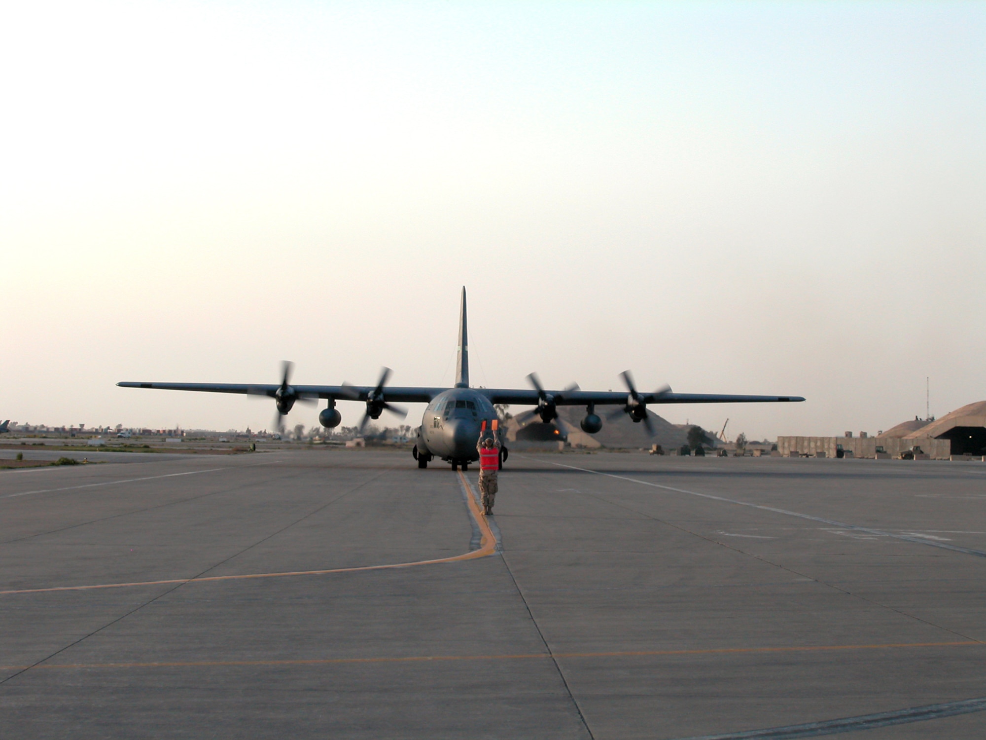 Airman 1st Class Richard Rump marshals an arriving C-130 Hercules to its designated parking spot March 20 at Balad Air Base, Iraq.  Airmen from the 332nd Expeditionary Maintenance Squadron's transient alert section handle about 3,000 aircraft a month. (U.S. Air Force photo/Master Sgt. Bryan Ripple) 