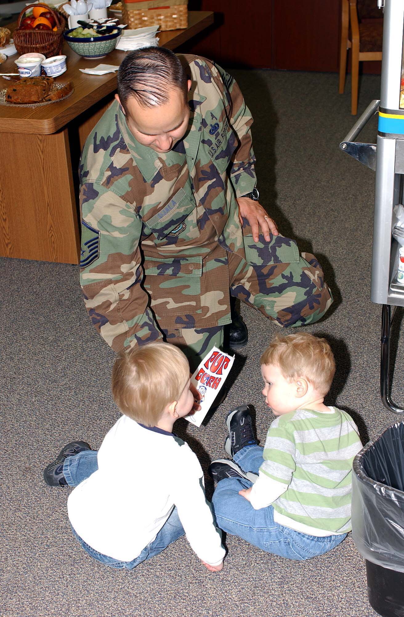 Master Sgt. Wayne Ojala, Airmen and Family Readiness Center superintendent, shares some popcorn with children during an open house event at the center here March 28.  The event, which included several base agencies, highlighted the resources available to base personnel and family members. (U.S. Air Force photo/Tech. Sgt. Joseph Kapinos)