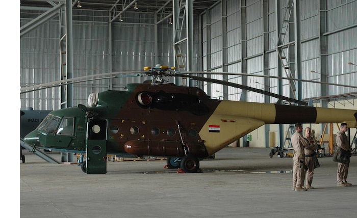 Military transition team members gather next to a newly refurbished helicopter at New Al Muthana in Baghdad, Iraq. The helicopters will be flown out of Taji Air Base. (U.S. Air Force photo/Tech. Sgt. Kevin Williams)
