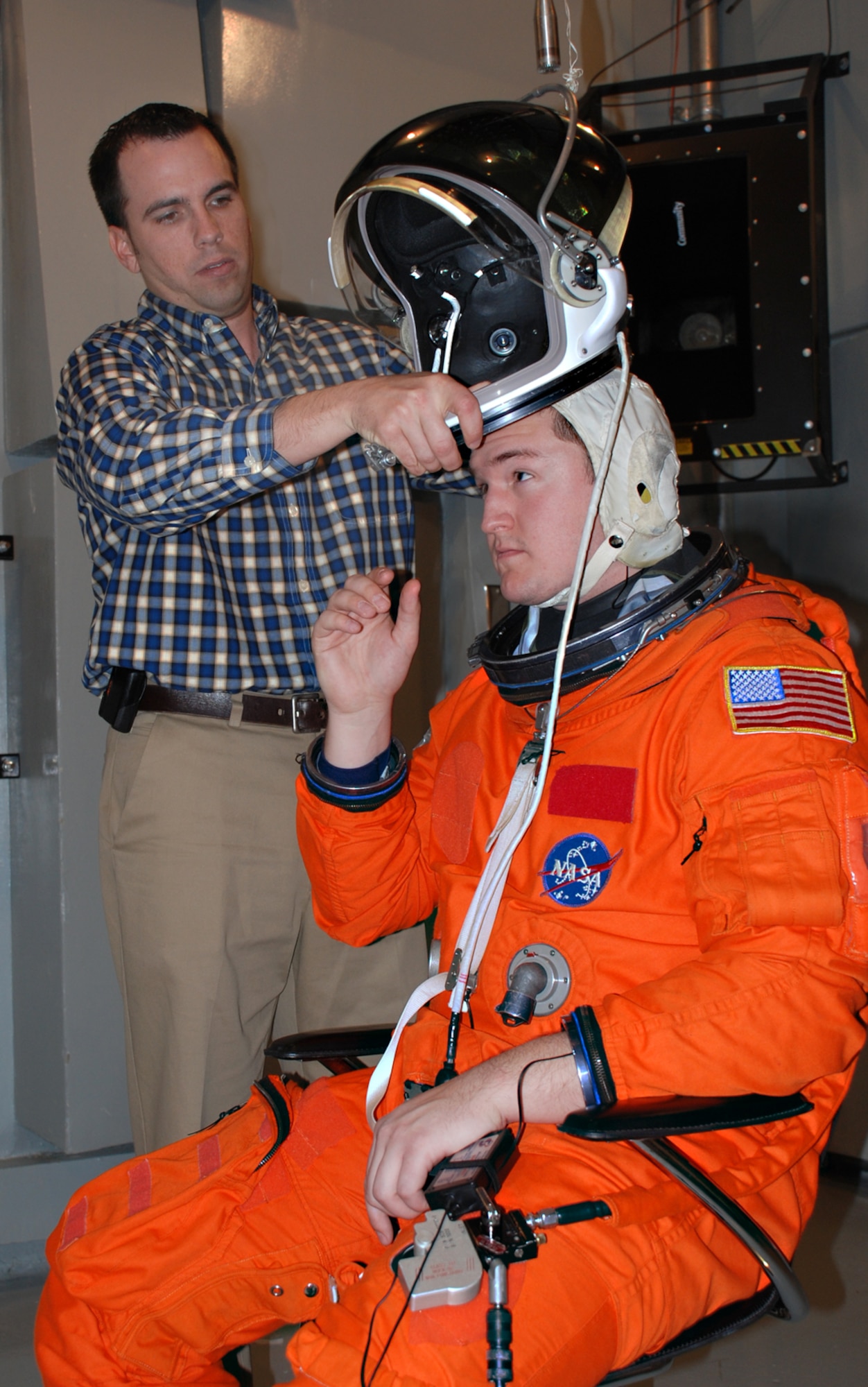 Engineer Dustin Gohmert of NASA’s Johnson Space Center installs a launch/entry helmet over the communications cap worn by test subject John Vinskey of General Dynamics Advanced Information Systems. NASA and the Air Force Research Laboratory’s Human Effectiveness Directorate are conducting tests to determine the level of hearing protection that the equipment provides. (Photo by Chris Gulliford, AFRL/HE)