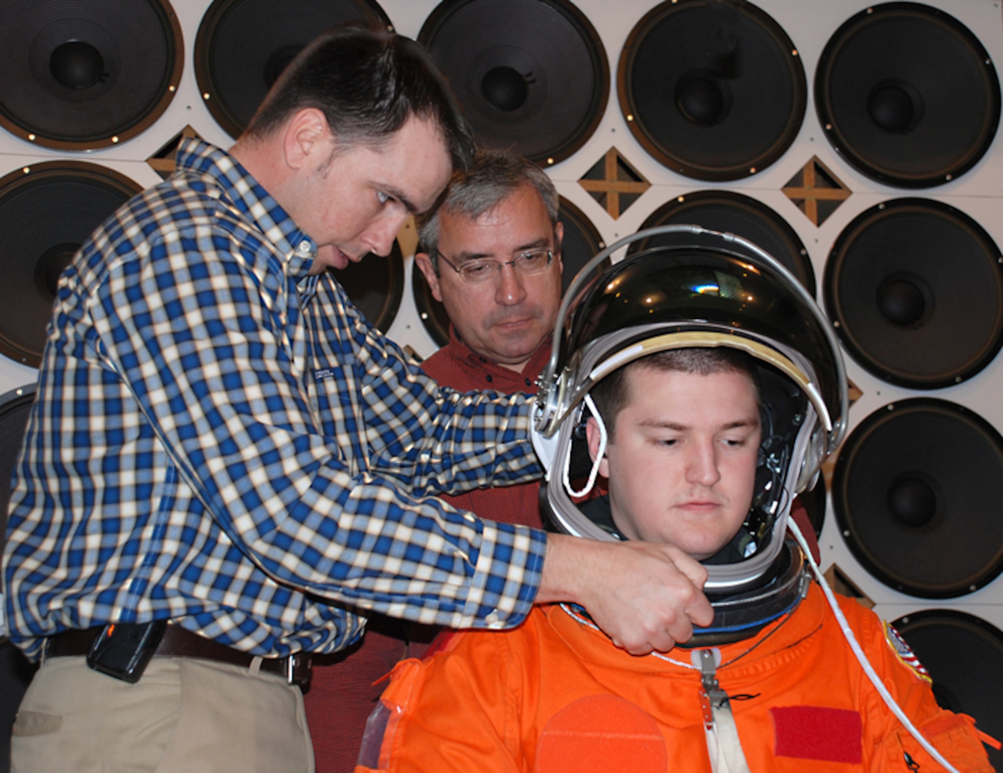 Engineer Dustin Gohmert of NASA’s Johnson Space Center installs a launch/entry helmet over the communications cap worn by test subject John Vinskey of General Dynamics Advanced Information Systems as audiologist Dr. Richard W. Danielson of the National Space Biomedical Research Institute observes. NASA and the Air Force Research Laboratory’s Human Effectiveness Directorate are conducting tests to determine the level of hearing protection provided by a new communications system. (Photo by Chris Gulliford, AFRL/HE)