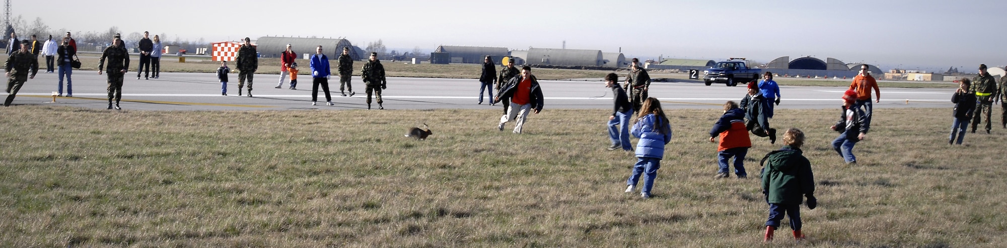 Volunteers attempt to herd a rabbit toward nets at the center of the flightline. Because the rabbits have no natural predators on base, their population increases and becomes an aircraft hazard.  (U.S. Air Force photo by Airman 1st Class Liliana Moreno) 