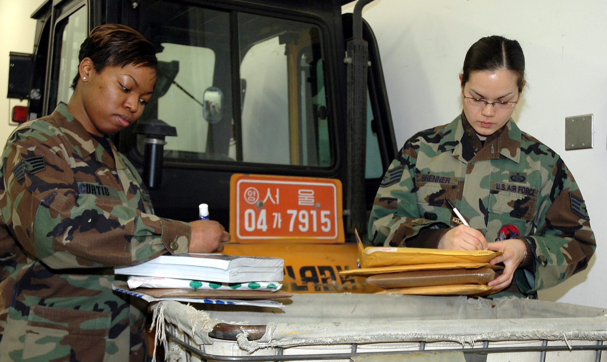 OSAN AIR BASE, Republic of Korea --  Staff Sgts. LeeVette Curtis (left) and Kimberly Brenner, 303rd Intelligence Squadron, write up PS Form 3907 to be distributed to mail boxes. The form is the yellow card military members find when they have a package to pick up. (U.S Air Force photo by Tech. Sgt. Michael O'Connor)