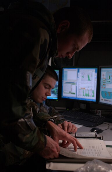 OSAN AIR BASE, Republic of Korea --  Staff Sgt. Joshua Rapp (left) and Senior Airman Steven Fanis, 51st Operations Support Squadron, review weather forecasting regulations Monday during the most recent exercise here. (U.S. Air Force photo by Airman Jason Epley)