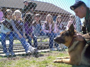 Girl Scout Troop 1354 from Poquoson watches as Senior Airman Shane Larson, 1st Security Forces Squadron, prepares military working dog Drak for a demonstration here March 30. The scouts showed their support for deployed troops by giving Hampton Roads families the opportunity to buy cookies for deployed Airmen. During the month-long cookie sale, the girls collected more than 60 boxes of cookies and presented them to the 1st Security Forces Squadron before the military working dog demonstration. (U.S. Air Force photo/Airman 1st Class Chase S. DeMayo)