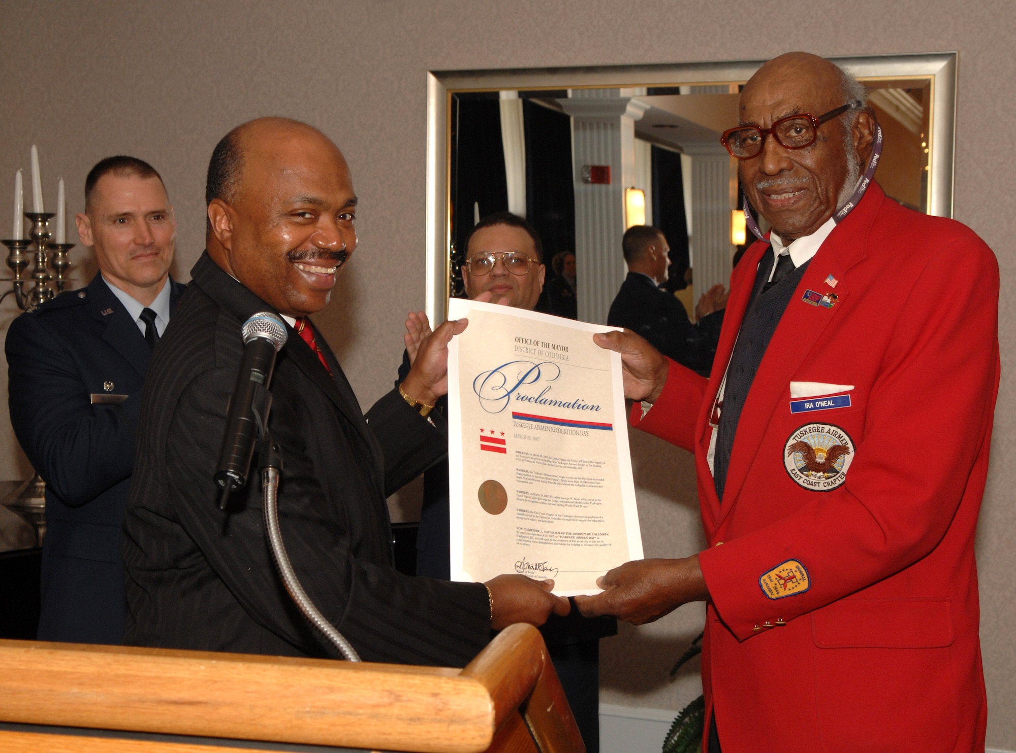 Kerwin Miller, executive office of Veterans Affairs, presents Ira O'Neal with a proclamation paper declaring Tuskegee Airman Day in Washington, D.C., at the dedication ceremony of the "Tuskegee Room" at the Bolling Air Force Base Club March 28. The Tuskegee Airmen received the Congressional Gold Medal from President George W. Bush March 29, the highest civilian honor bestowed by Congress. (U.S. Air Force photo/Airman 1st Class Timothy Chacon)