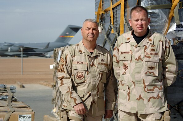 BALAD AIR BASE, Iraq -- (From right) Maj. Preston McFarren, Aerial Port Flight commander, and Chief Master Sgt. Steven Saxon, superintendent, stand next to pallets prepared for delivery to servicemembers downrange at the cargo yard at Balad Air Base, Iraq. Major McFarren and Chief Saxon are assigned to the 332nd Expeditionary Logistics Squadron with the 332nd Air Expeditionary Wing. They are deployed here together from the 443rd Airlift Wing?s 26th Aerial Port Squadron at Lackland Air Force Base, Texas. Balad Air Base is the aerial port hub for all of Iraq and the busiest cargo aerial port in the Department of Defense. (U.S. Air Force photo by Senior Airman Candace Romano)