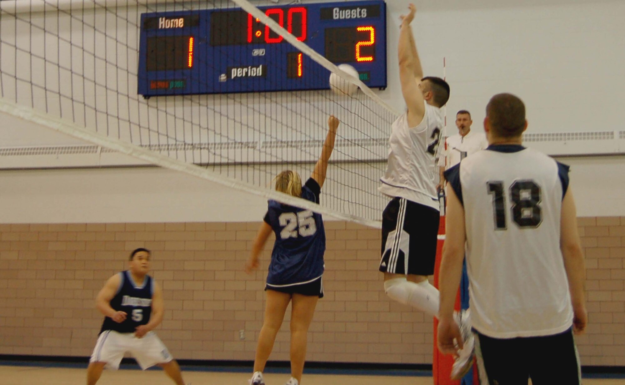 Donald Johnson, 319th Service Squadron's player/coach, is ready to block as Tess Armstrong (number 25), 319th Mission Support Squadron, dinks the ball to Services. (U.S. Air Force photo/Staff Sgt. Amanda Callahan) 