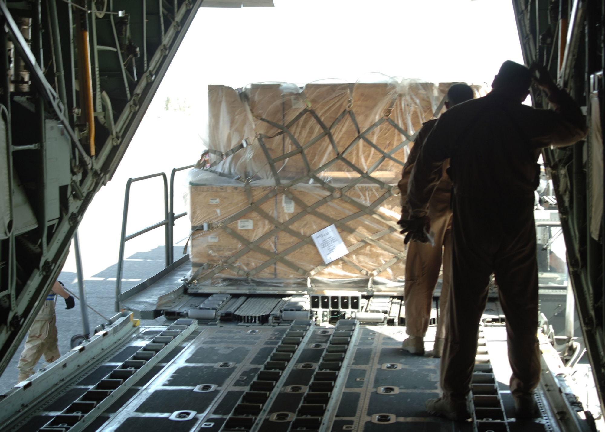 BALAD AIR BASE, Iraq - An Iraqi Air Force air crewman and U.S. Air Force Master Sgt. John Gahan, who serves with the Coalition Air Force Transition Team, secure pallets of humanitarian relief supplies for delivery to Iraqi citizens victimized in a vehicle-borne improvised explosive device attack March 27 that killed 80 Iraqis, wounded 140 more and destroyed more than 20 homes. The food, tents and other humanitarian supplies are being flown to Tal Afar on an Iraqi Air Force C-130 Hercules today. (U.S. Air Force photo/Capt. Ken Hall)