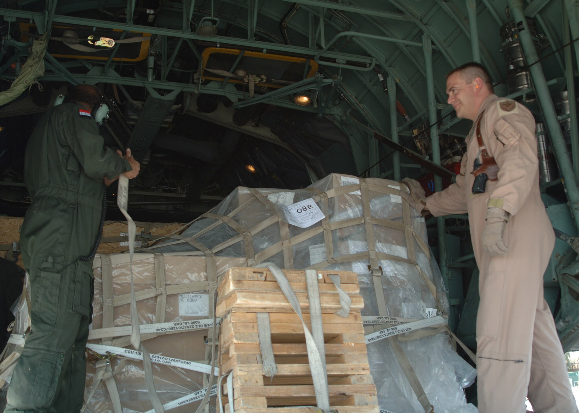 BALAD AIR BASE, Iraq - An Iraqi Air Force crew member and U.S. Air Force Master Sgt. John Gahan, who serves with the Coalition Air Force Transition Team, secure pallets of humanitarian relief supplies for delivery to Iraqi citizens victimized in a suicide vehicle-borne improvised explosive device attack March 27 that killed 80 Iraqis, wounded 140 more, and destroyed more than 20 homes. The supplies, including food, tents and other humanitarian relief supplies, are being flown to Tal Afar on an Iraqi Air Force C-130 Hercules today. (U.S. Air Force photo/Capt. Ken Hall)
