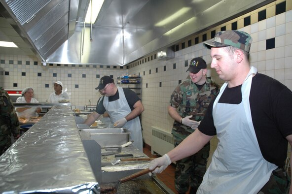 YOUNGSTOWN AIR RESERVE STATION, Ohio—In the foreground, Air Force Reserve Staff Sgt. Dan D'Annunzio cooks hamburger patties during the midday meal at the 910th Services Squadron Dinning Hall.  At his right, Airman 1st Class Tom Burke, Senior Airman Tony Behanna and Senior Airmen Asia Triplett assist in the food preparation for more than 1,400 reservists assigned to Youngstown Air Reserve Station. U.S. Air Force Photo/Tech. Sgt. Ken Sloat