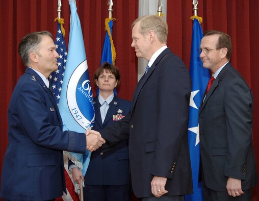From left, Electronic Systems Center Vice Commander Maj. Gen. Art Rooney shakes Peter Zimmerman’s hand during Mr. Zimmerman’s instatement as the 554th Electronic Systems Wing’s Honorary Wing Commander March 23 at the Minuteman Club. Frank Weber, 554 ELSW director, far left, passed the Air Force’s 60th Anniversary flag to Mr. Zimmerman during the ceremony. ESC Command Chief Master Sergeant Lisa Sirois, center back, presented the flag to the base leaders. (US Air Force Photo by Jan Abate)

