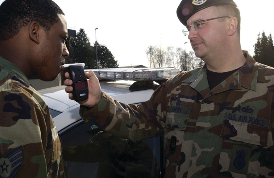 SPANGDAHLEM AIR BASE, GERMANY -- Tech. Sgt. Scott Kuhrt, 52nd Security Forces Squadron, demonstrates the use of a breathalyzer on fellow security forces member Staff Sgt. David Hudson Wednesday. This breathalyzer is carried by members of the  52nd SFS to emergency scenes to detect if an individual is under the influence of alcohol. (Photo by Staff Sgt. Raymond Mills)