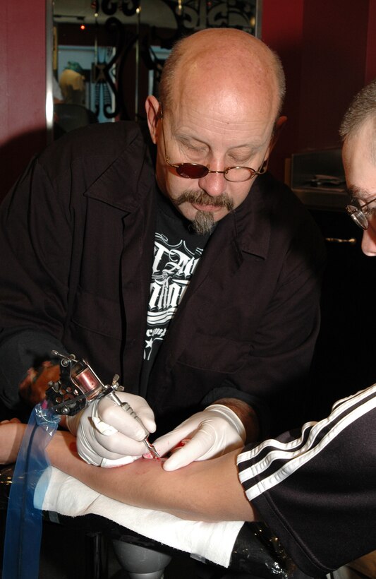 Max Kilbourne, a tattoo artist with Hart and Huntington Tattoo Company in Waikiki touches up a Marine's tattoo March 31.  On April 1, the Marine Corps new tattoo policy banning visible, sleeved tattoos went into affect.